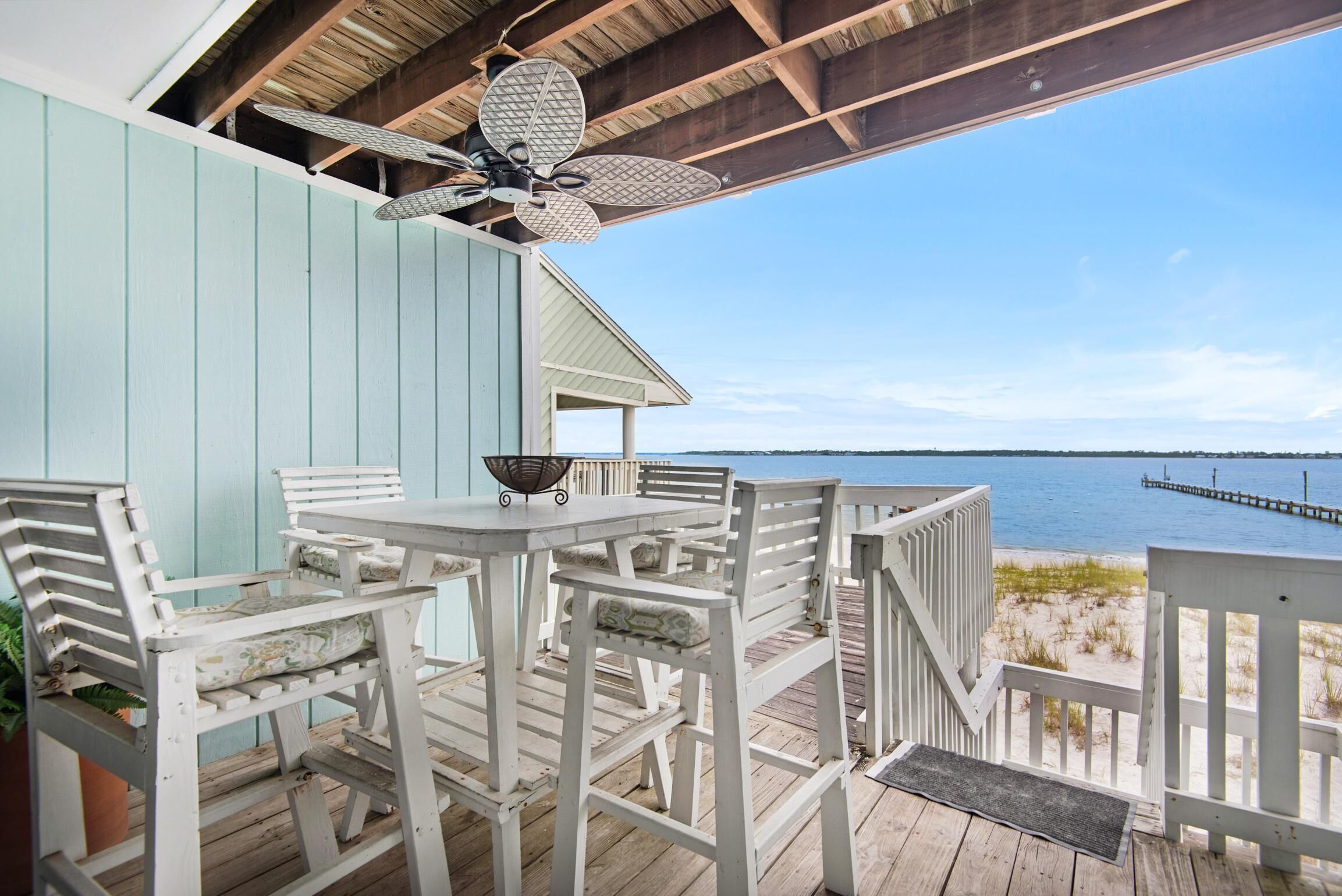 A wooden deck with white furniture and a view of the ocean.