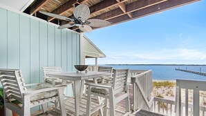 A wooden deck with white furniture and a view of the ocean. - Boardwalk D6 (Pensacola Beach)