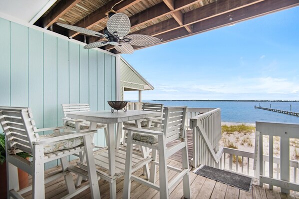 A wooden deck with white furniture and a view of the ocean.