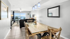 A dining area with a wooden table and chairs, a ceiling fan, and pendant lights. - Boardwalk D6 (Pensacola Beach)