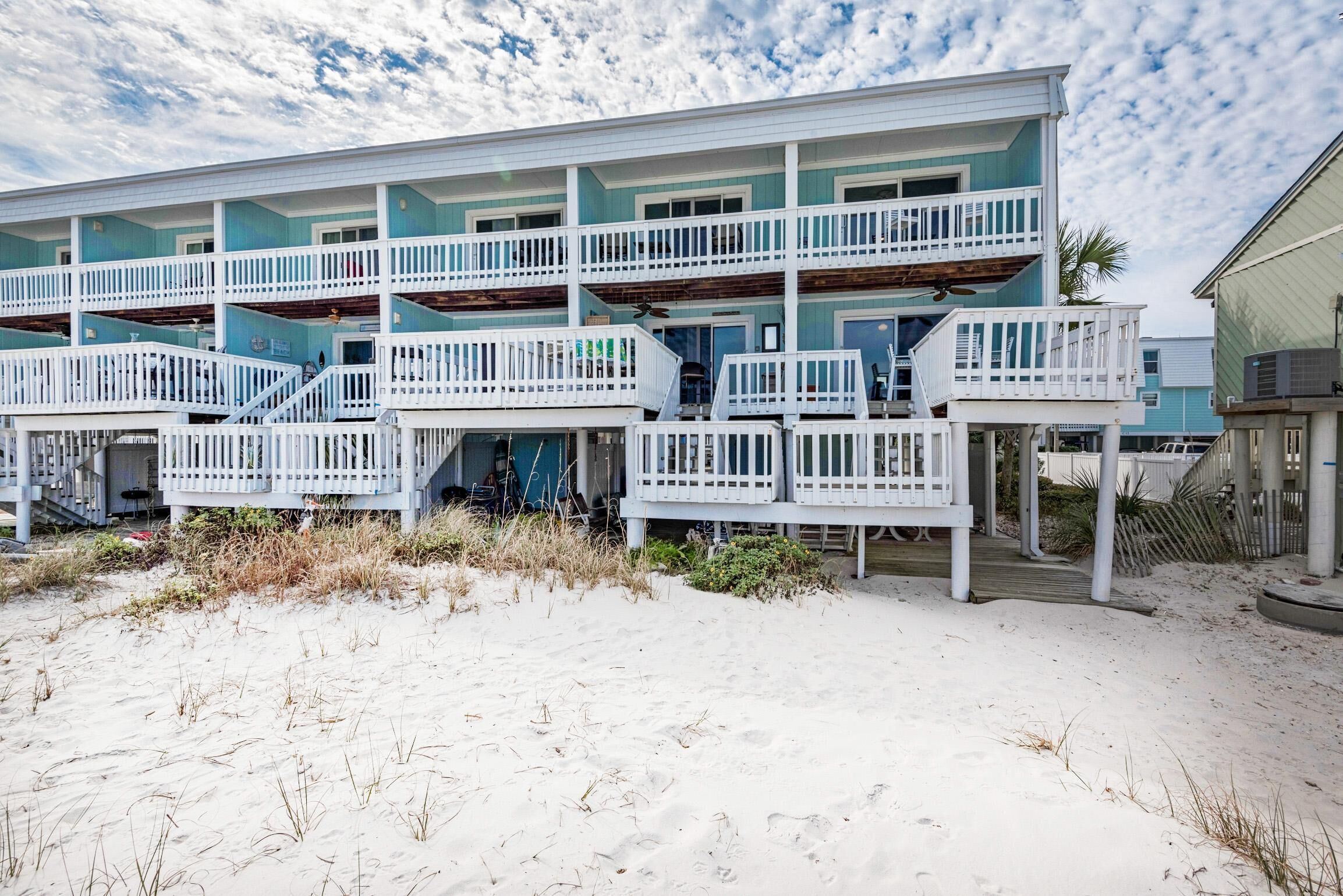 A beachfront building with multiple balconies and a sandy beach in front.
