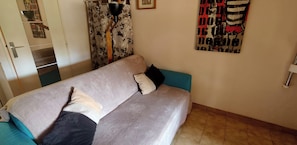 A room with a sofa, a lamp, a painting, and a door.