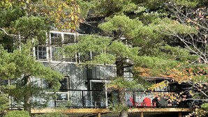 Un immeuble à plusieurs étages, doté d’une façade en bois, d’un porche abrité et offrant une vue sur une étendue d’eau.