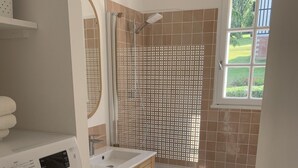 A compact bathroom with a washing machine, a sink, and a shower area. - Apartment with swimming pool - near train station (Villers-sur-Mer)