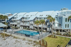 A beachfront hotel with multiple-story buildings, a swimming pool, and palm trees. - Labahia 123 (Pensacola Beach)