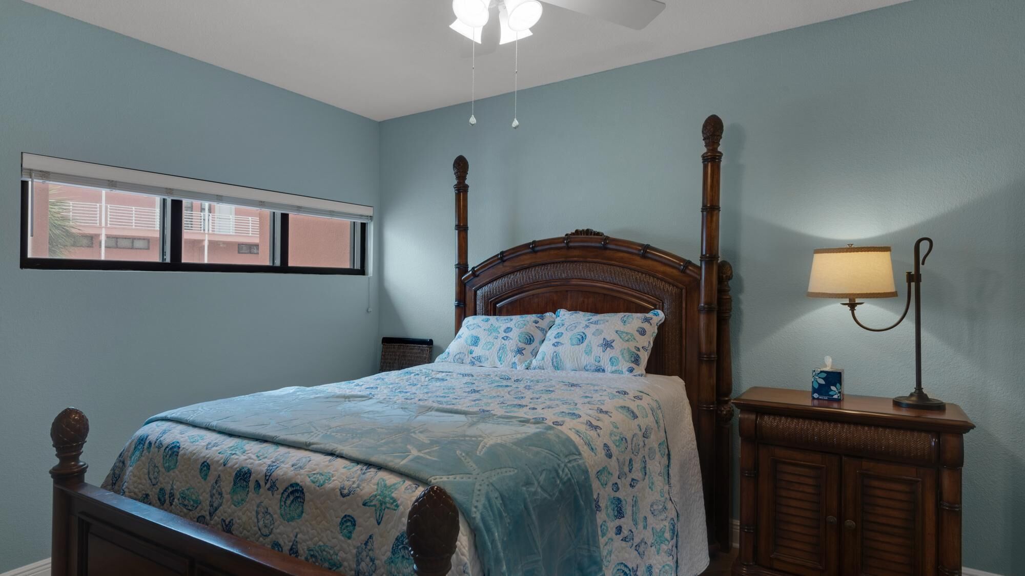 A bedroom with a bed, a nightstand, a lamp, and a window.