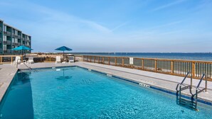 A swimming pool with a wooden deck and a view of the ocean. - Palm Beach Club 4-127 Parrot-dise Palms (Pensacola Beach)