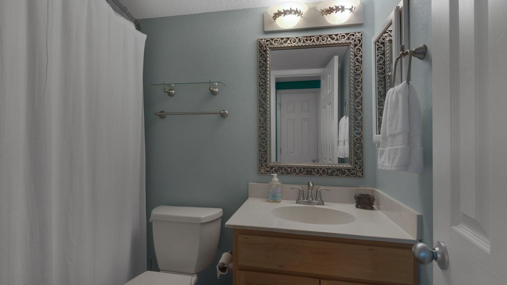 A bathroom with a toilet, sink, and mirror.
