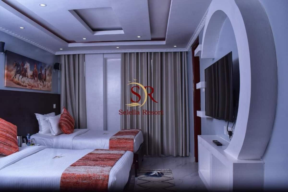 A hotel room with two beds, a TV, and a painting on the wall.