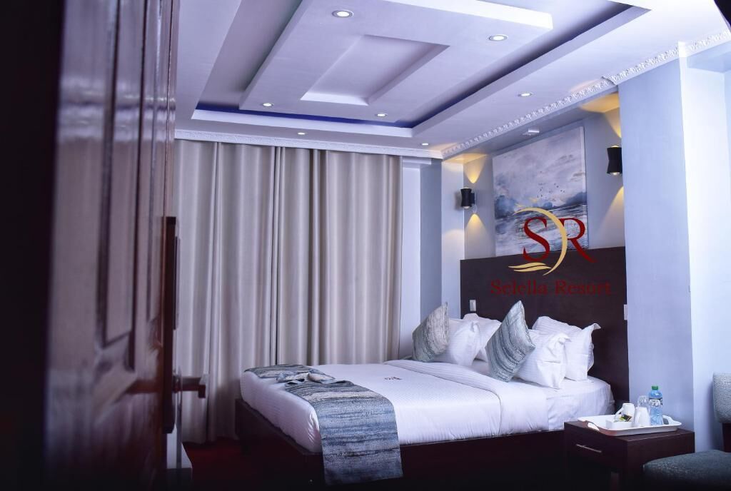 A modern hotel room with a large bed, a nightstand, and a wall-mounted TV.