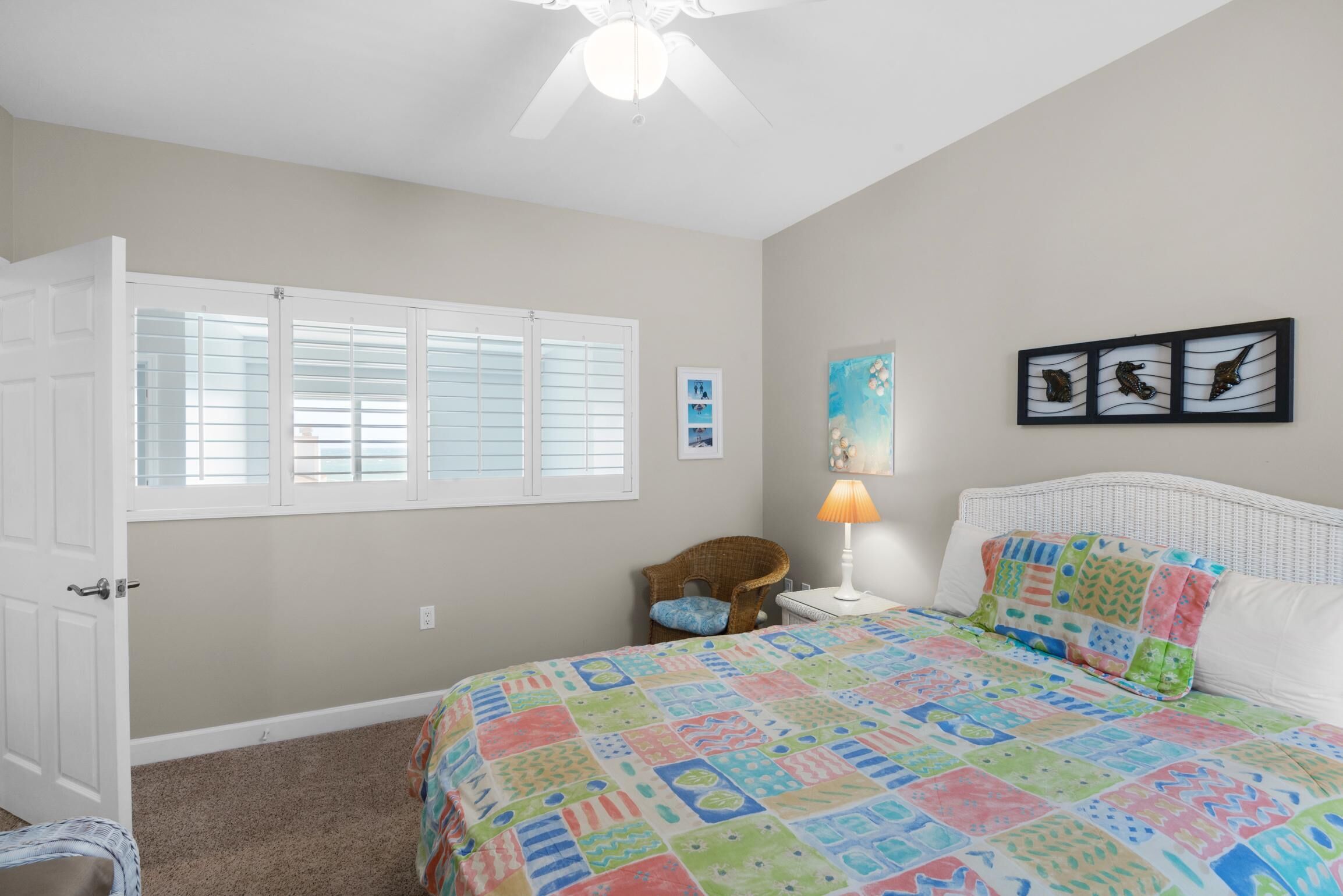 A bedroom with a bed, a chair, a lamp, and a window with blinds.