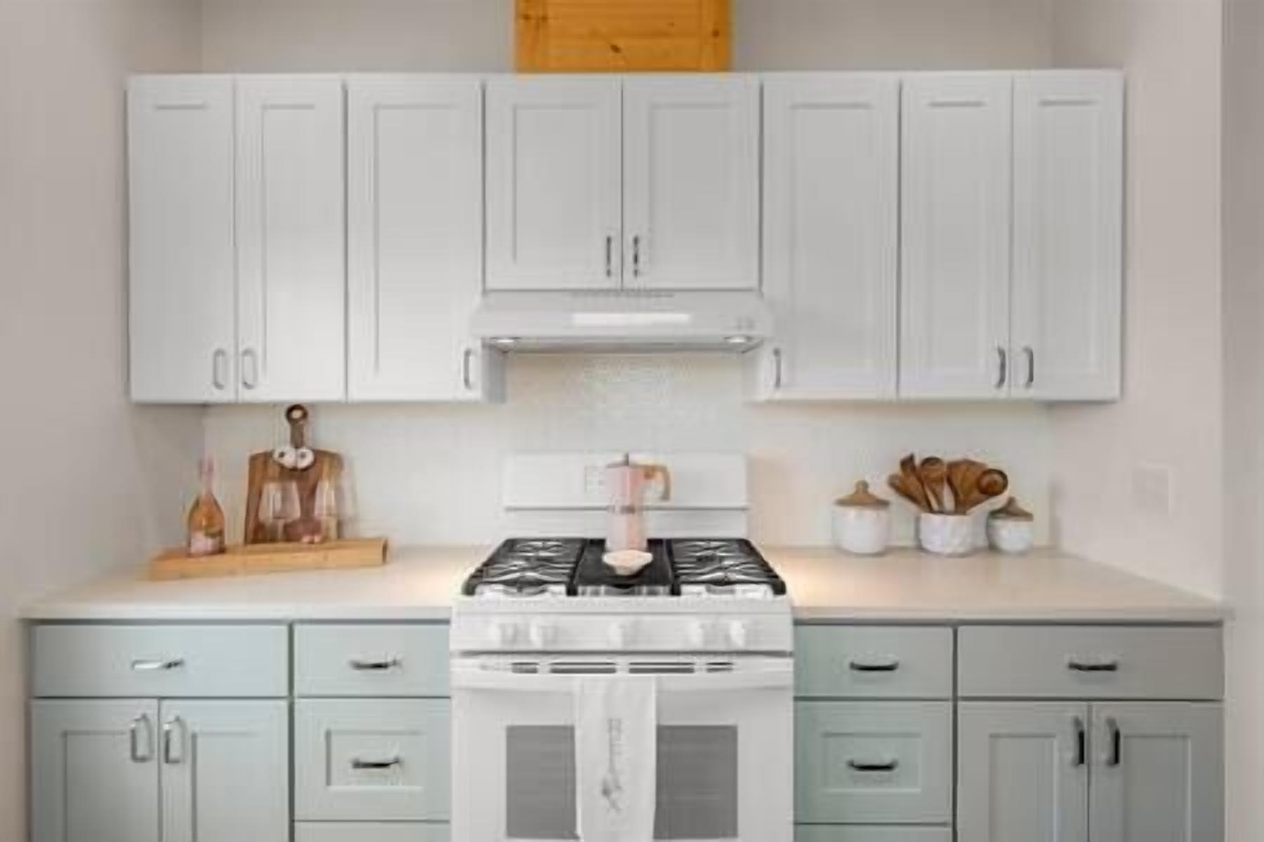 A kitchen with white cabinets, a stove, and a wooden ceiling.