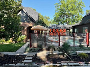 A motel with a pool, a covered patio, and a brick building. - the treehouse w/pool, hot tub, relaxing courtyard (Houston)