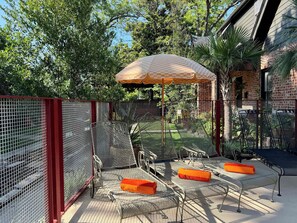 A fenced outdoor area with metal chairs and an umbrella.