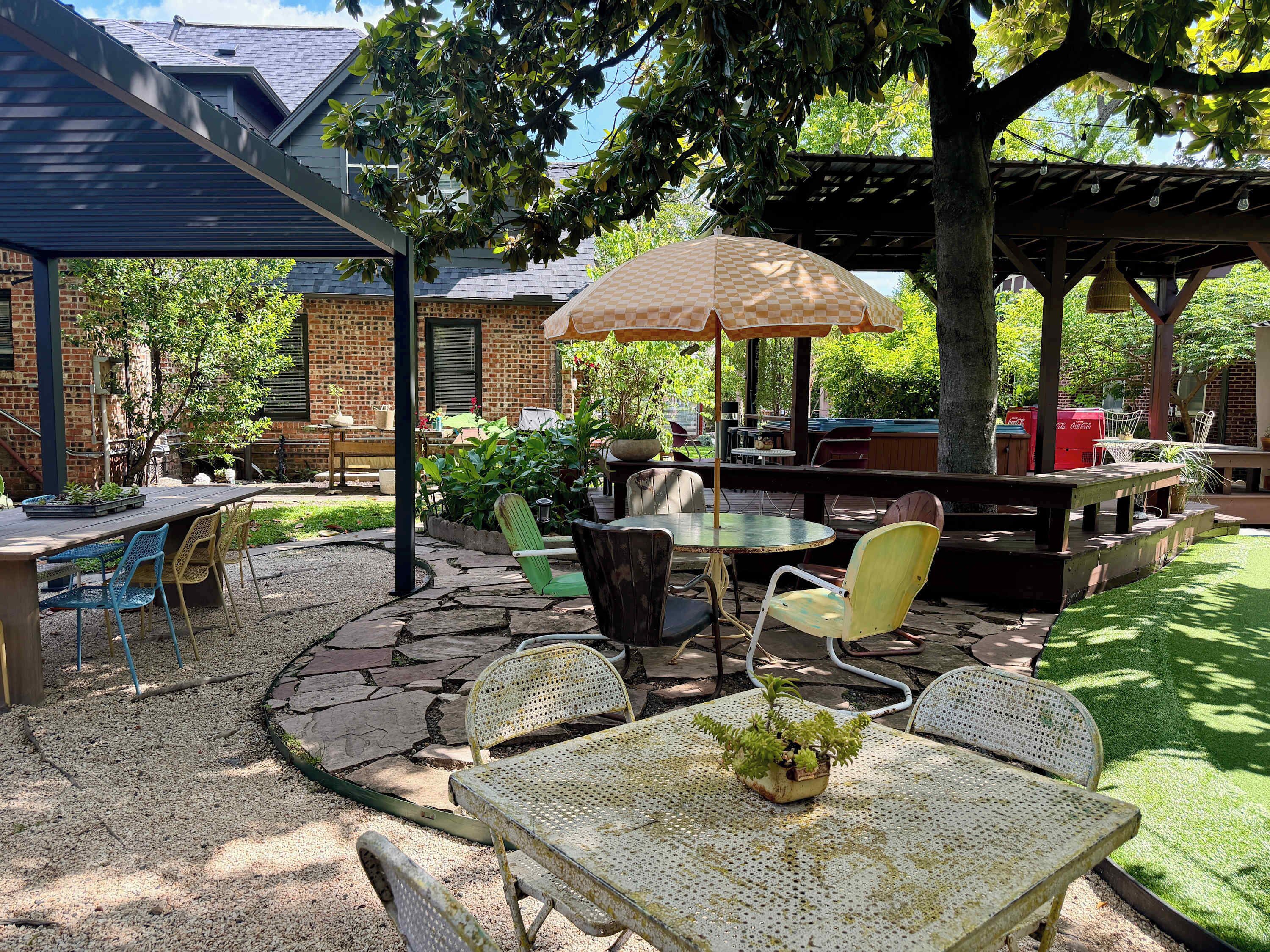 Eine Terrasss mit überdachter Sitzgruppe, einem Tisch und Stühlen sowie einem dekorativen Sonnenschirm.