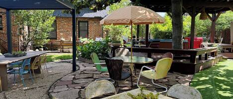 Eine Terrasss mit überdachter Sitzgruppe, einem Tisch und Stühlen sowie einem dekorativen Sonnenschirm.