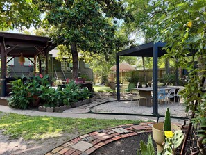 A patio area with a pergola, outdoor seating, and a garden with various plants.
