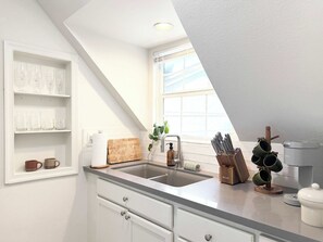 A kitchen with a built-in sink, a window, and a shelf with glassware. - the treehouse w/pool, hot tub, relaxing courtyard (Houston)