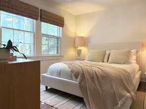 A bedroom with a bed, bedside table, lamp, window with blinds, and a potted plant. - the treehouse w/pool, hot tub, relaxing courtyard (Houston)