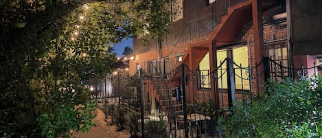 Un edificio con fachada de ladrillo, una escalera y una entrada protegida por una reja.