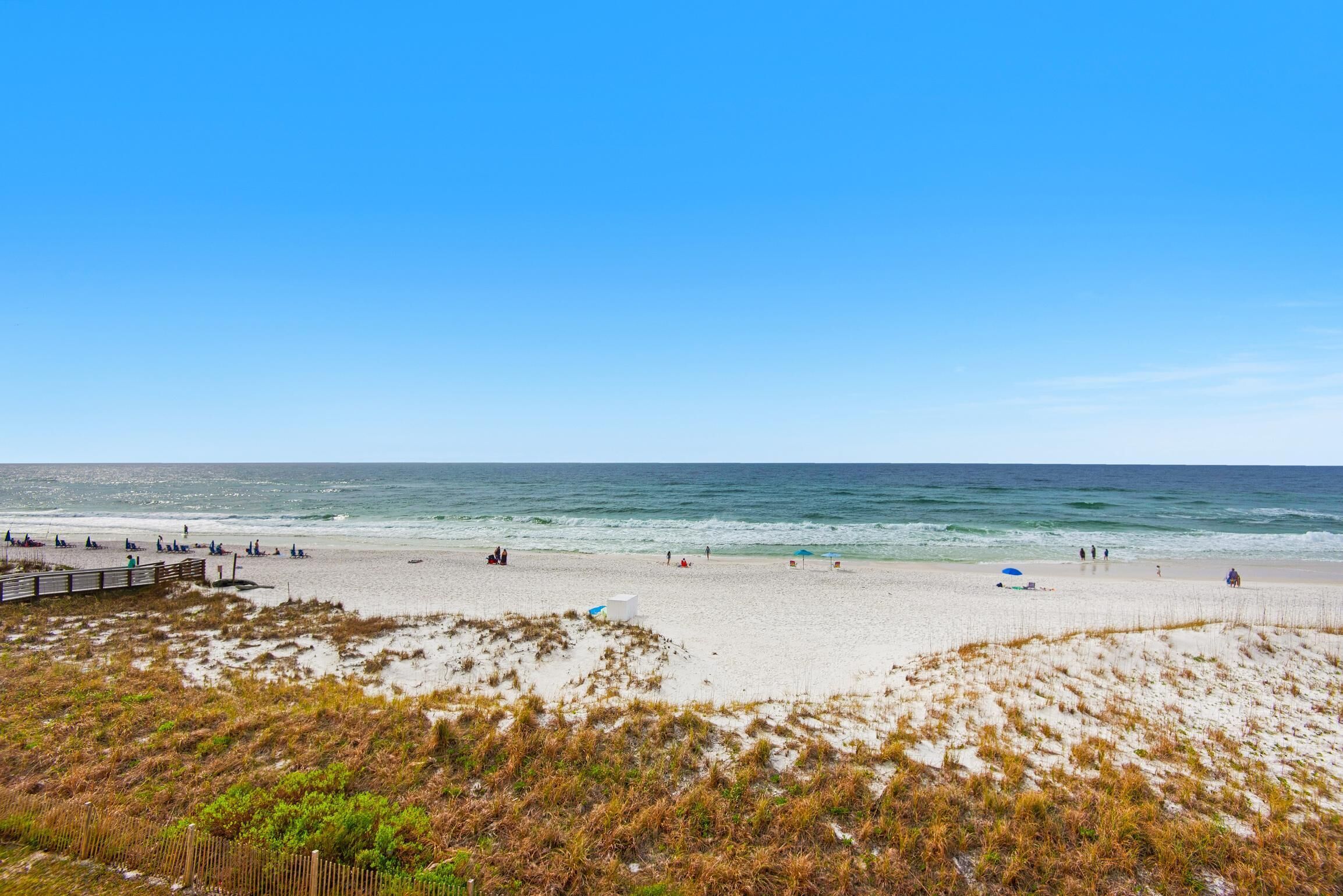 Ein Strand mit einem hölzernen Steg, Sandküste und Blick auf den Ozean.