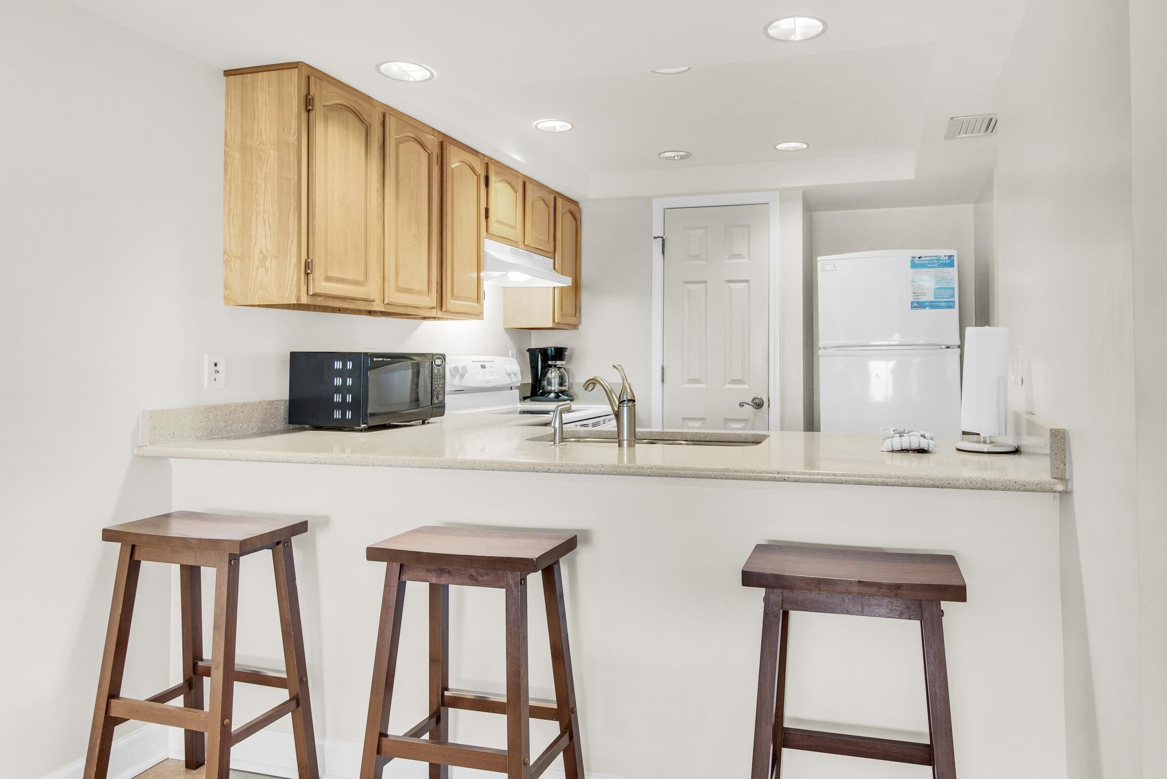 A kitchen with wooden cabinets, a microwave, a coffee maker, and a refrigerator.