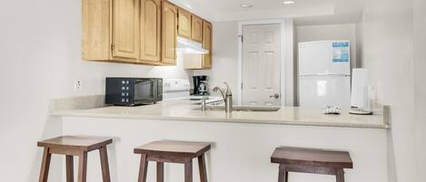A kitchen with wooden cabinets, a microwave, a coffee maker, and a refrigerator.