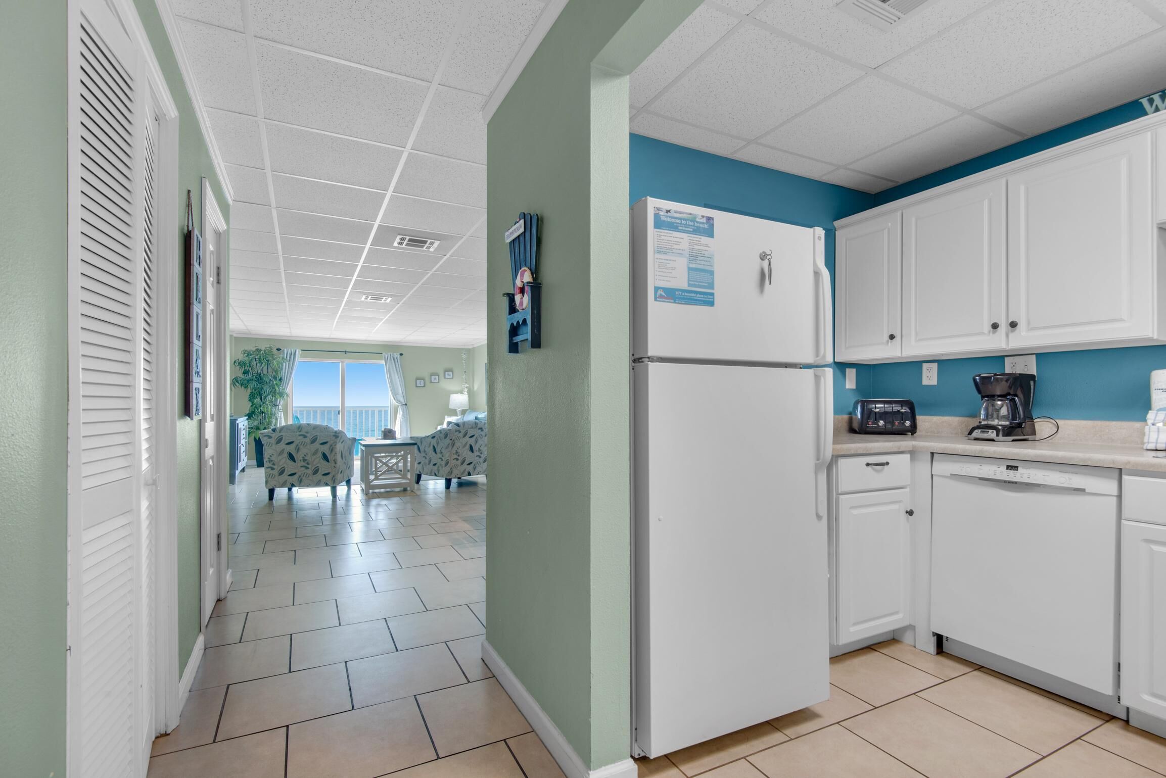 A kitchen with white cabinets, a refrigerator, and a coffee maker.