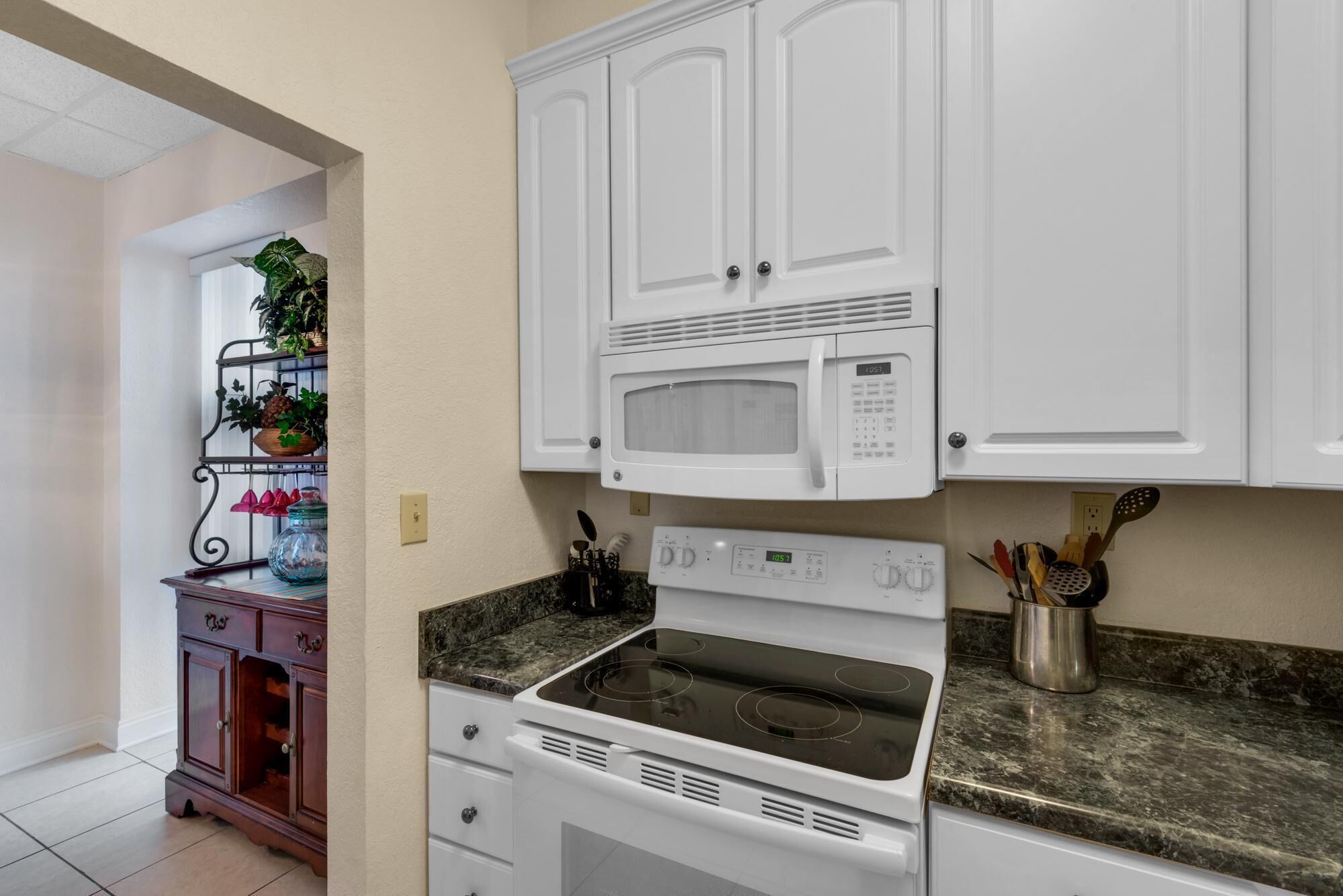 A kitchen with white cabinets, a microwave, an oven, and a granite countertop.