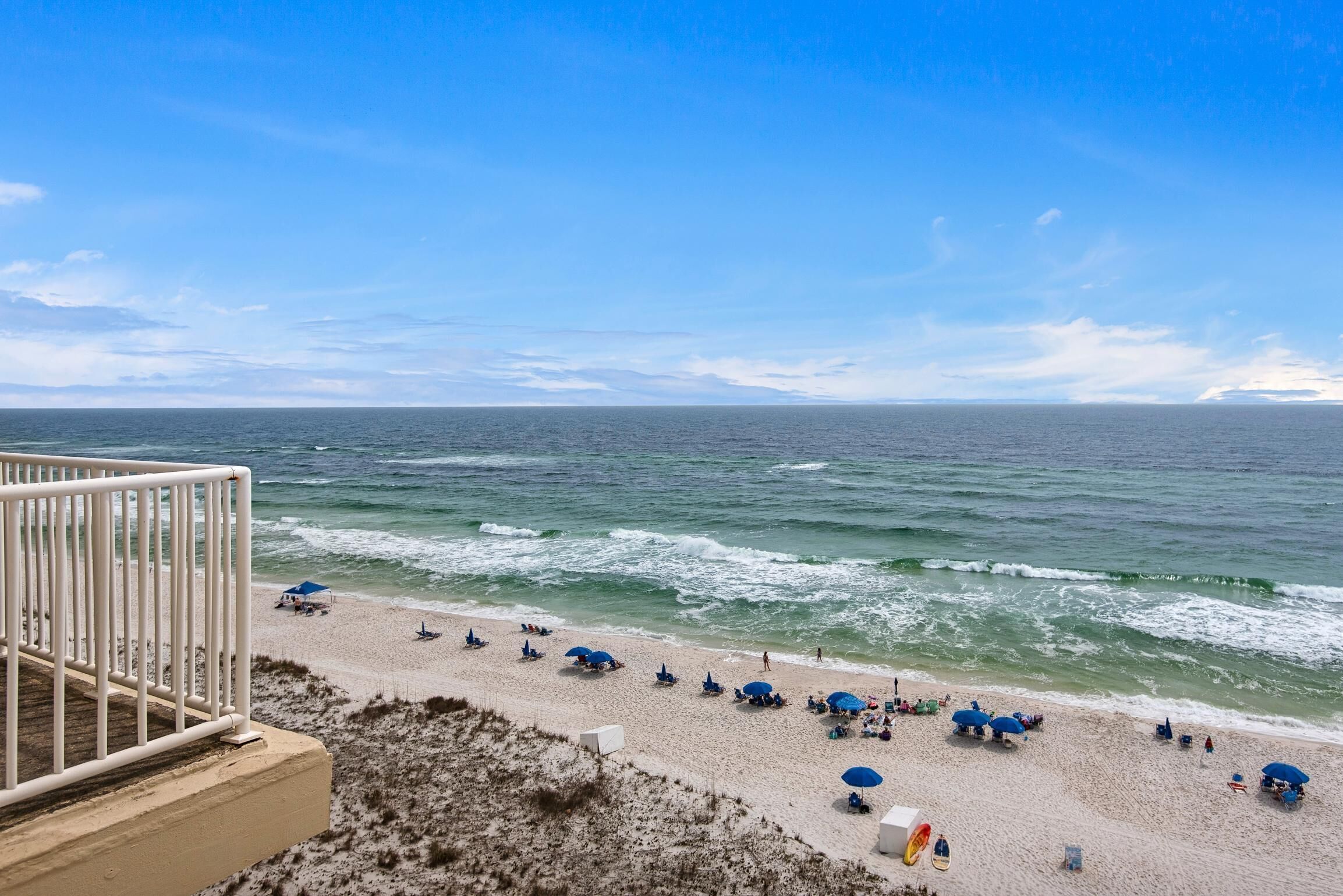Een strand met parasols en mensen.