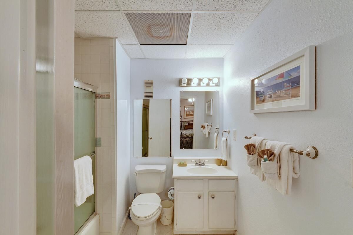 Un baño con inodoro, lavamanos, tocador y espejo con iluminación.
