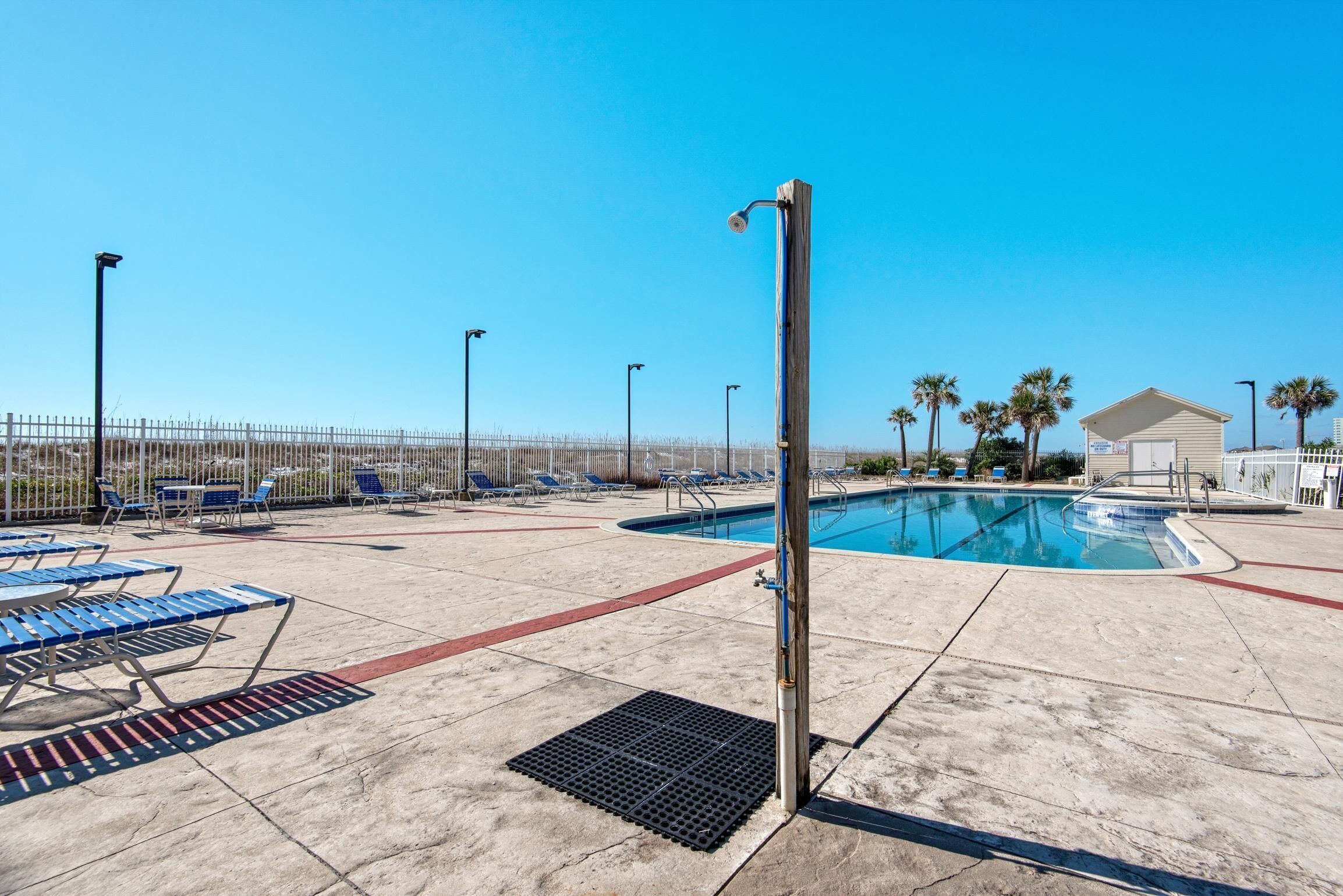 Un espace piscine comprenant des chaises longues, une piscine et une clôture.