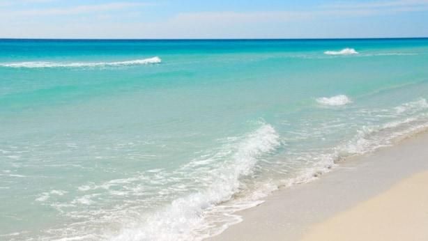 A beach with clear turquoise water and gentle waves. - Sans Souci Unit 601 (Pensacola Beach)