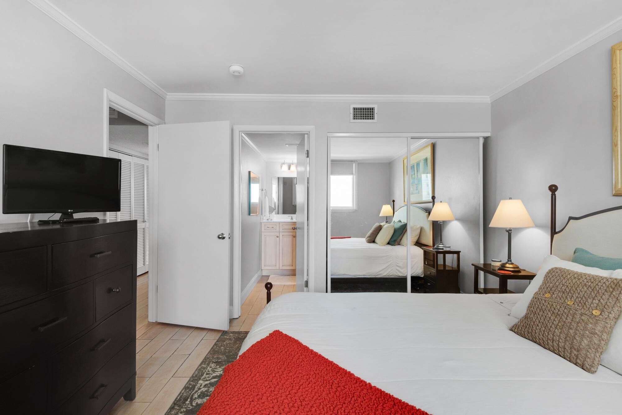 Een hotelkamer met een bed, nachtlampjes, een televisie en een kledingkast.