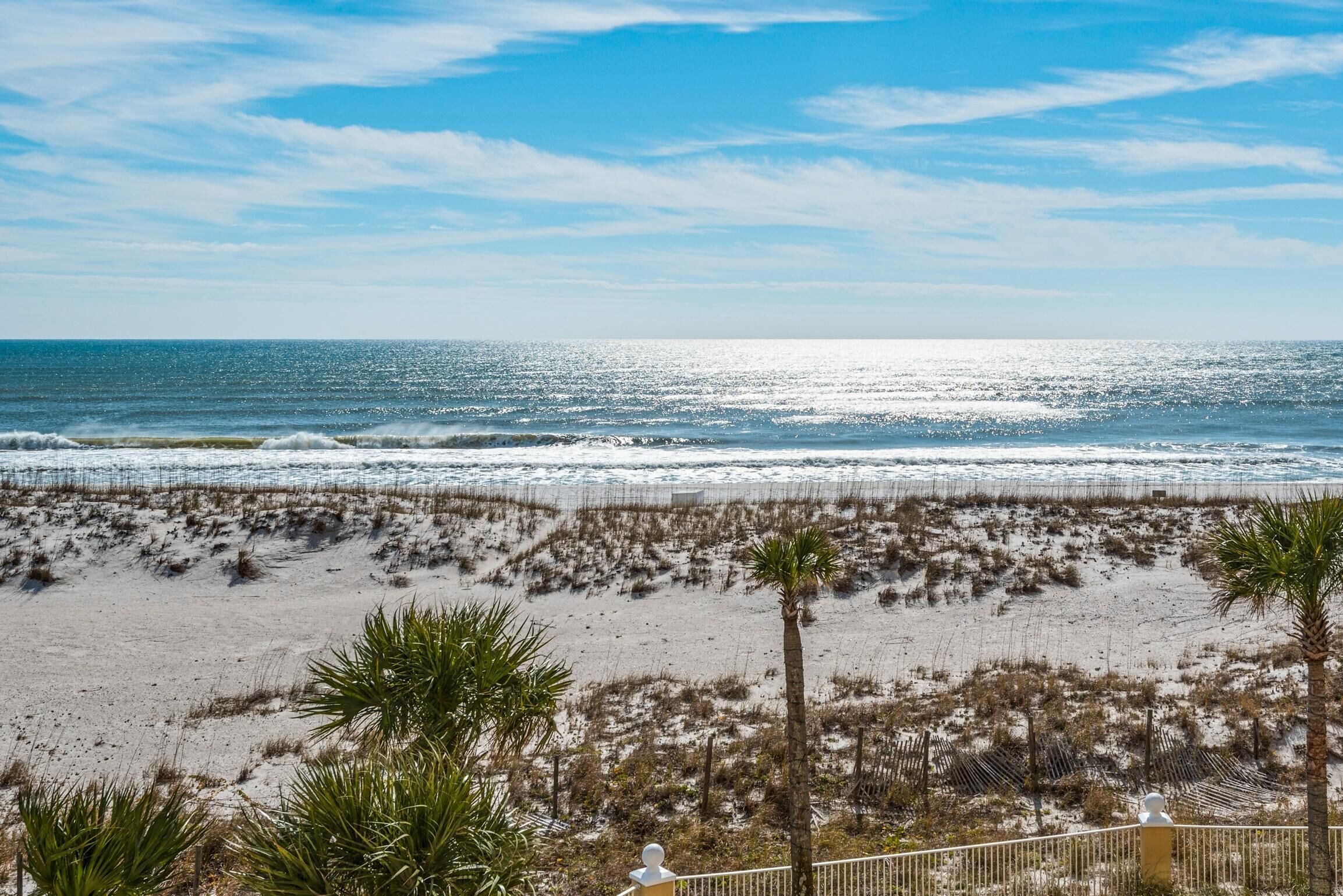A beach with sand, waves, and a clear sky.