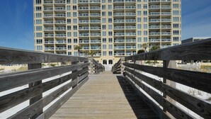 Une promenade en bois menant à un immeuble de grande hauteur doté de nombreux balcons.