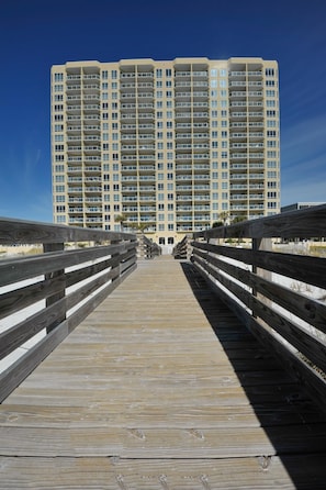 Une promenade en bois menant à un immeuble de grande hauteur doté de nombreux balcons.