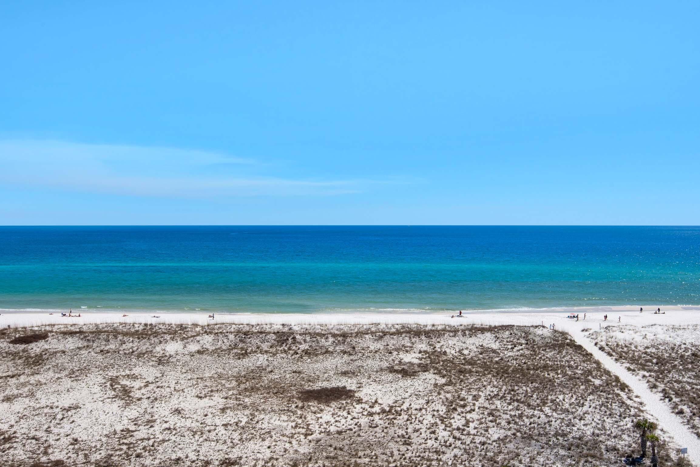 A beach with a clear blue sky and calm sea.