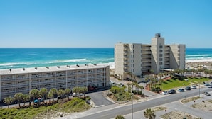 A coastal hotel with multiple floors, a parking area, and a view of the ocean. - Seahorse Unit M (Pensacola Beach)