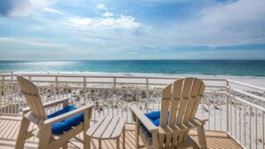 A beach view from a deck with two Adirondack chairs and a small table. - Seahorse Unit M (Pensacola Beach)