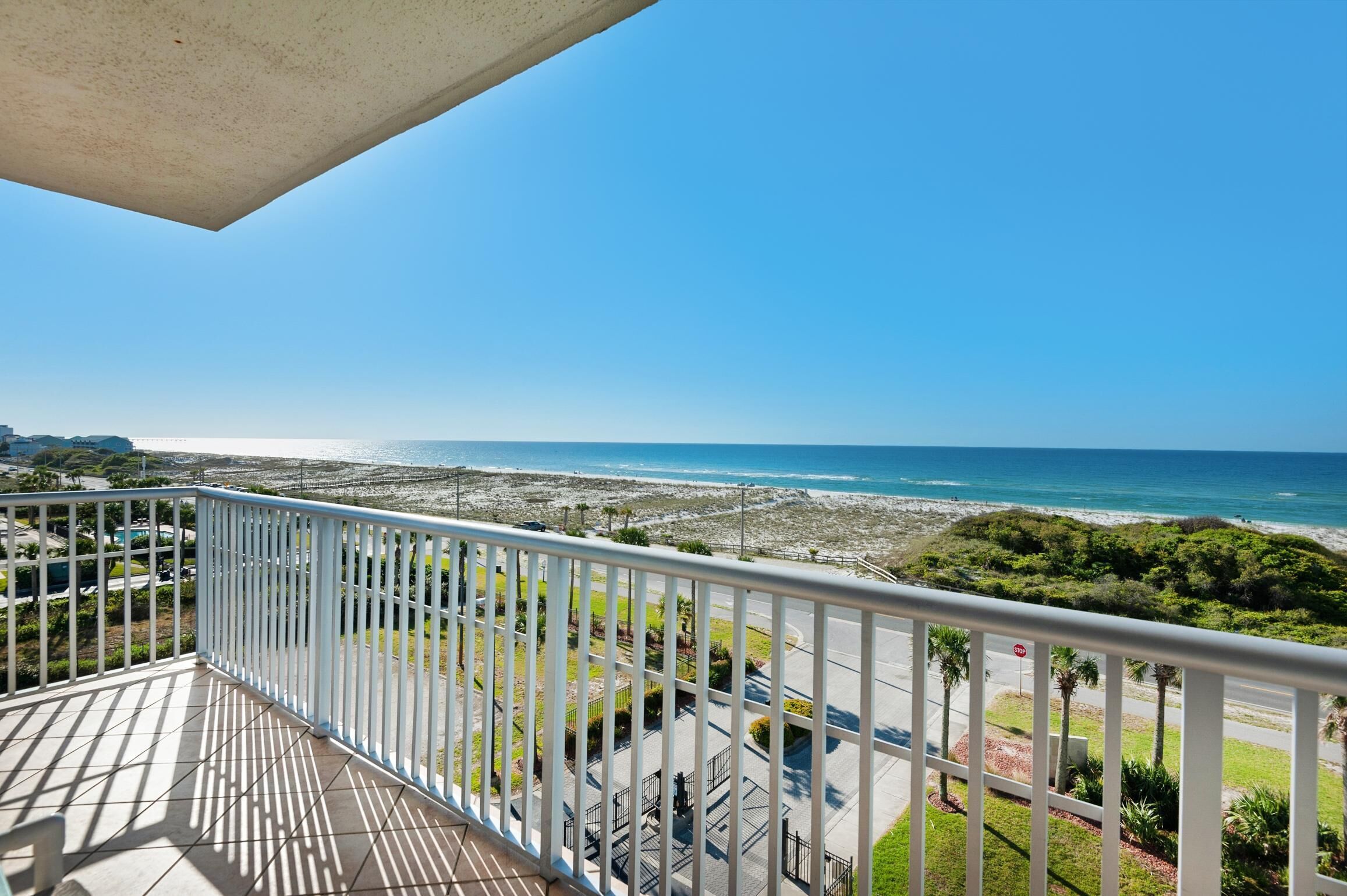 A balcony with a view of the beach and ocean.