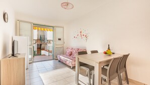 Una sala moderna con un sofá, una mesa de comedor, sillas y un televisor sobre un mueble.