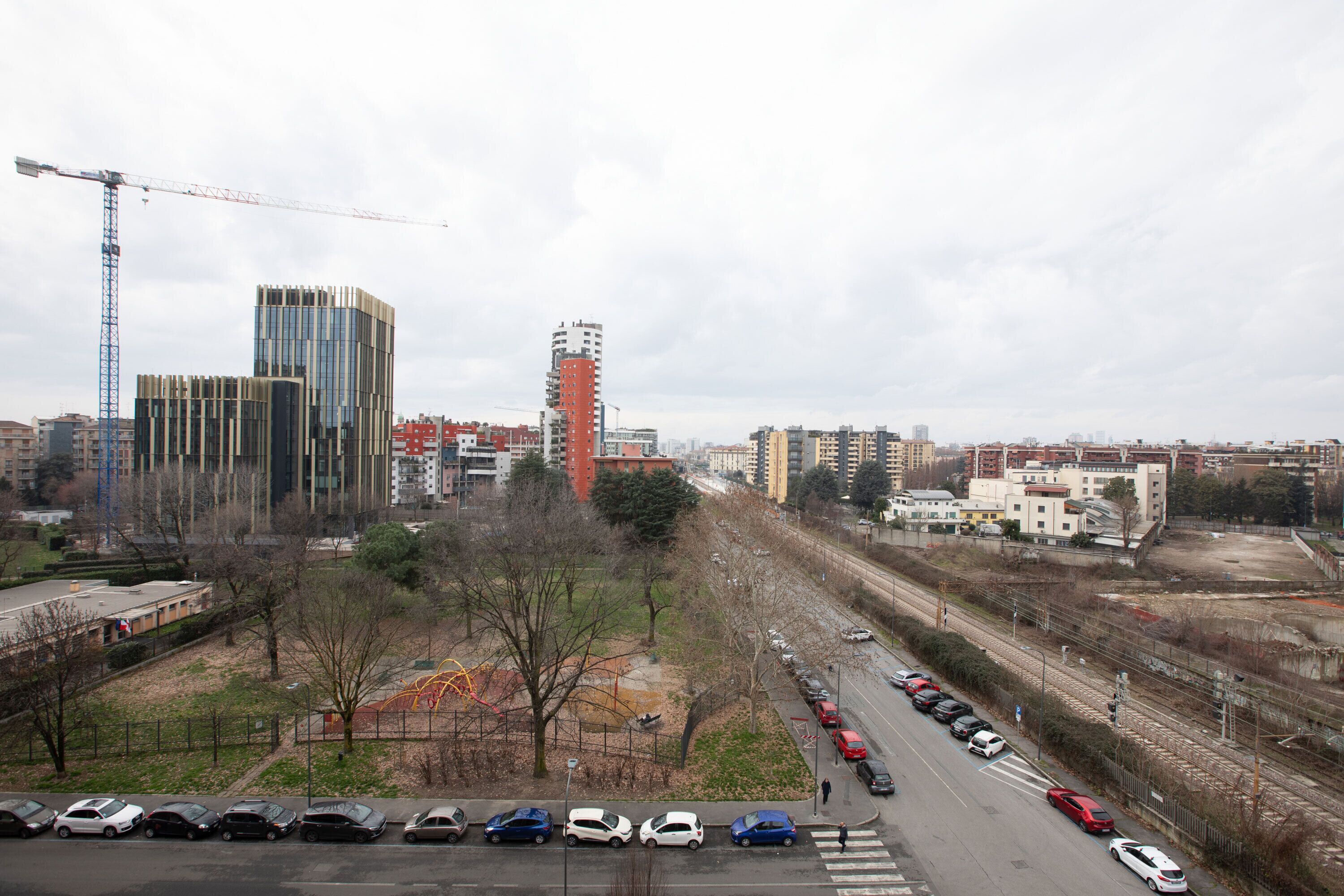 A cityscape with modern buildings, a parking lot, and a railway track.