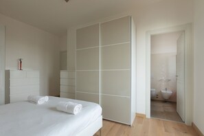 A bedroom with a bed, a wardrobe, and a bathroom visible through an open door. - Lo Spole Apartment by BarbarHouse (Milano)