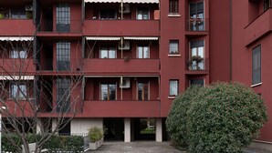 Un edificio rosso a più piani con balconi, condizionatori d'aria e piante in vaso.
