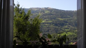 Une vue depuis une fenêtre donnant sur un paysage vallonné.