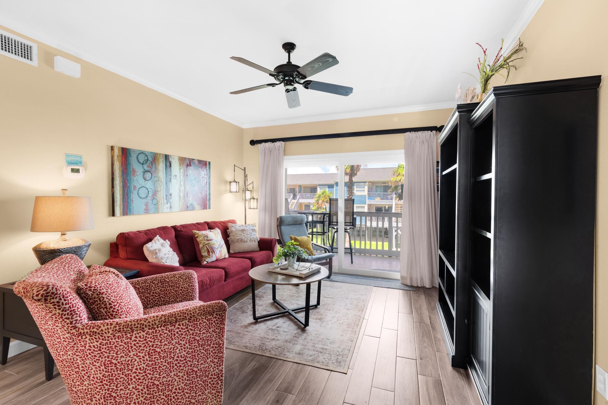 A living room with a red sofa, a leopard print chair, a coffee table, and a ceiling fan.