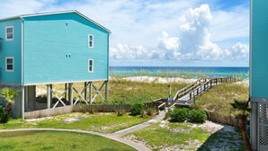 Un edificio turchese con un pontile in legno che conduce a una spiaggia.