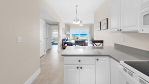 Een moderne keuken met witte kasten, een centraal eiland en een eethoek met uitzicht op de oceaan.