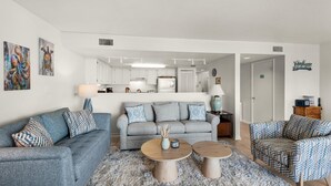 A modern living room with a grey sofa, two round coffee tables, and a patterned rug. - Starboard Village 423 (Pensacola Beach)